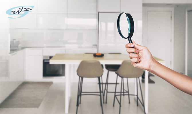 A hand holding a magnifying glass in a house looking for water leakage
