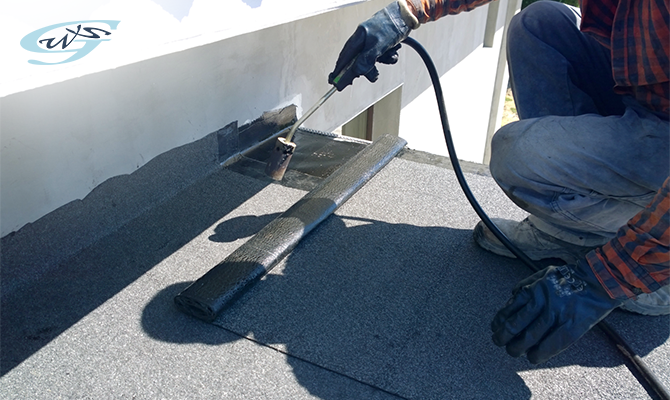 A worker waterproofs the roof using a welding torch fire
