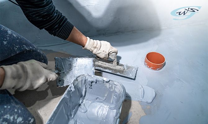 A worker applying waterproofing cement with a trowel.