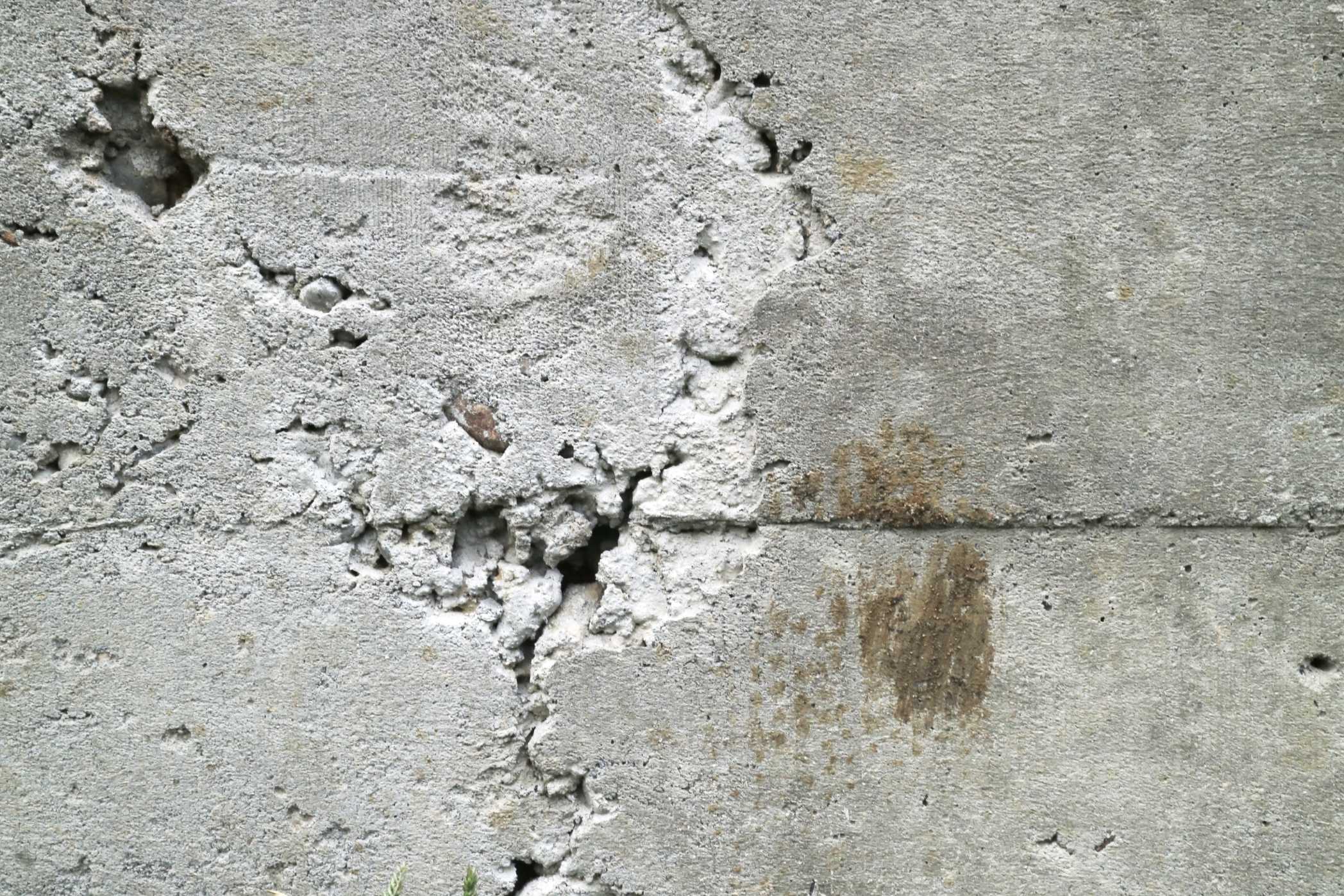 A rough concrete surface with deep cracks and honeycombing