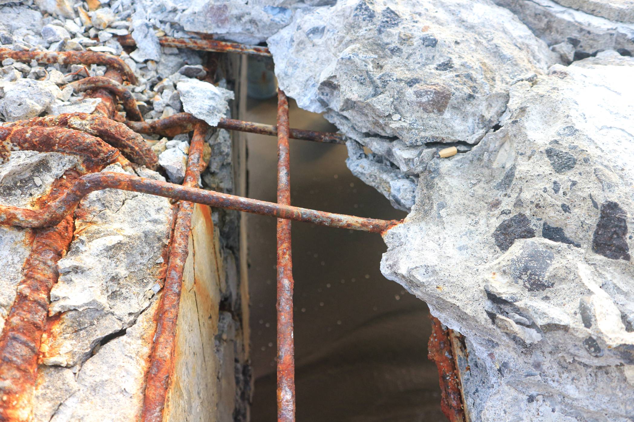 Exposed, rusted rebar within a crumbling concrete structure