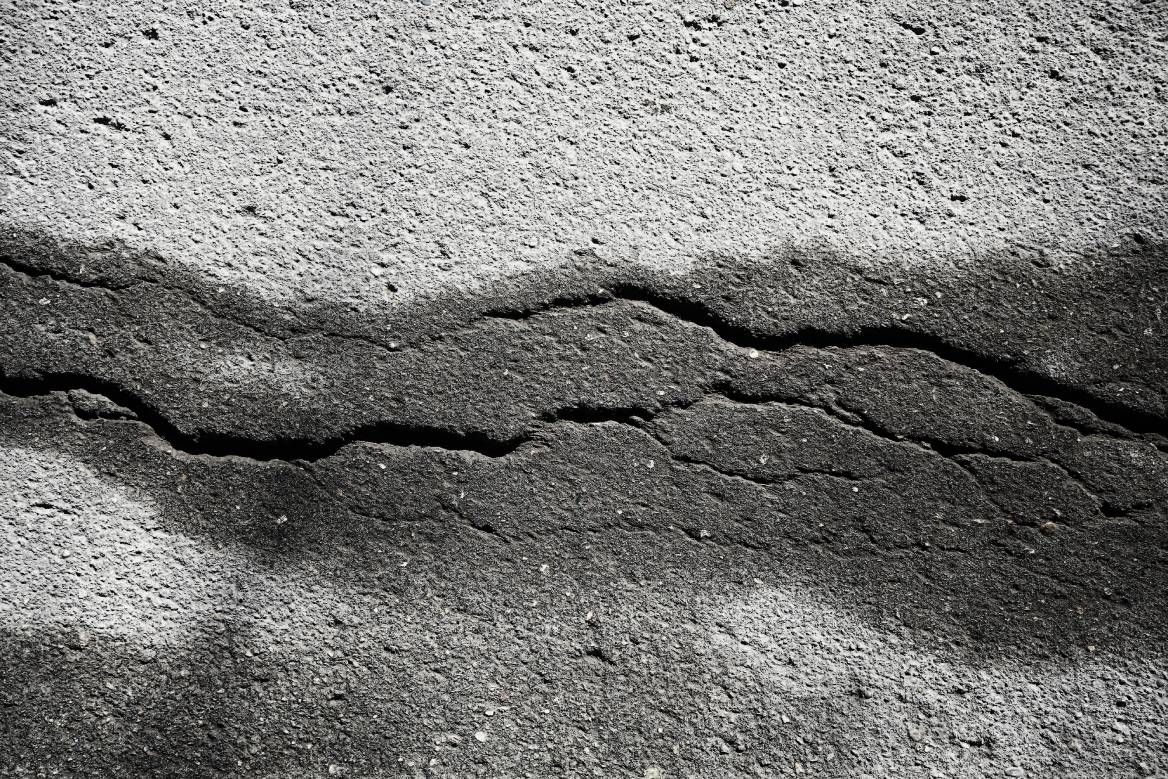 A large, horizontal crack running through a textured concrete wall
